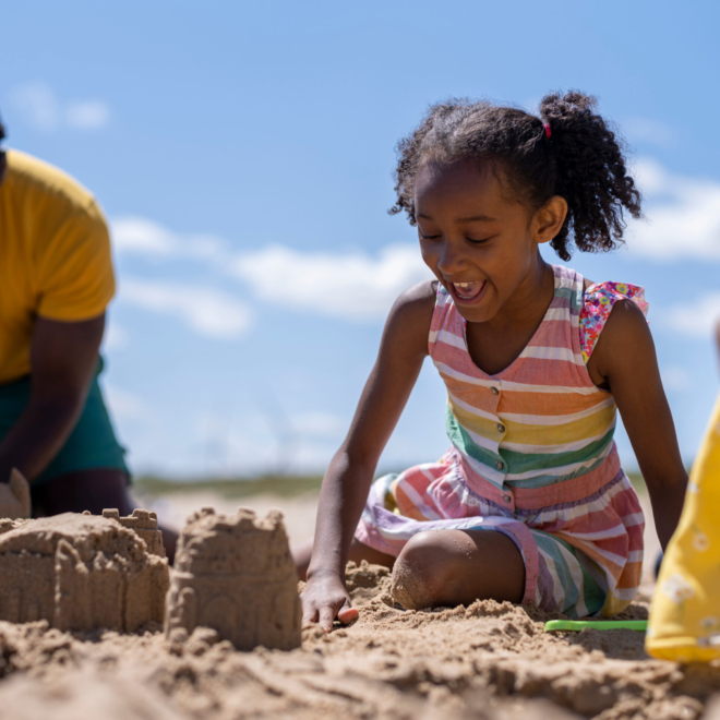 A family playing on a sandy beach building a sand castle
